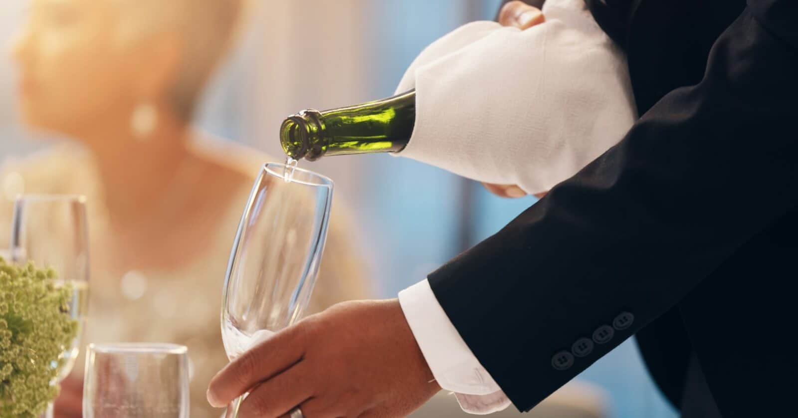 Waiter, hands and champagne in glass at restaurant for new year party, gala event and fine dining.